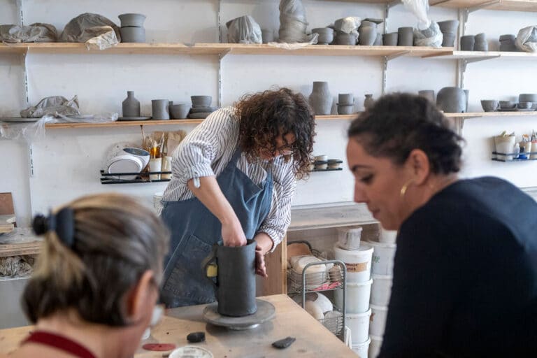 Artisane formatrice accompagnant une adulte lors d'une formation au CAP céramiste dans son atelier.