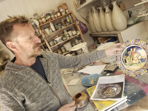 Artisan formateur présentant une pièce en décoration céramique dans son atelier