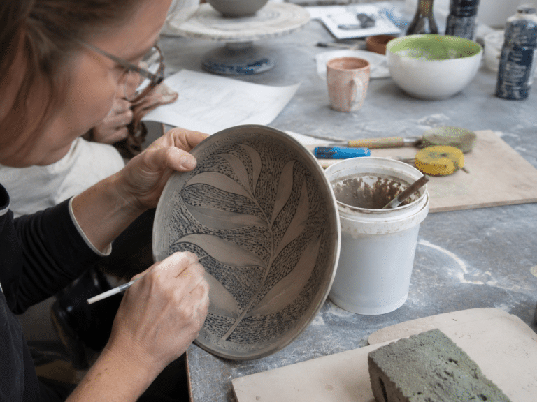 Apprentissage des techniques de décoration céramique sur une pièce en terre crue pendant une formation professionnelle