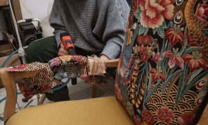 Stagiaire travaillant sur la réfection d’un fauteuil, dans le cadre d’une formation pour devenir tapissier
