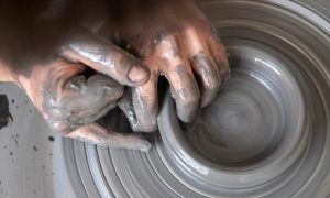 Mains d'un stagiaire façonnant l'argile sur un tour de potier lors d'une formation en tournage céramique à Montpellier