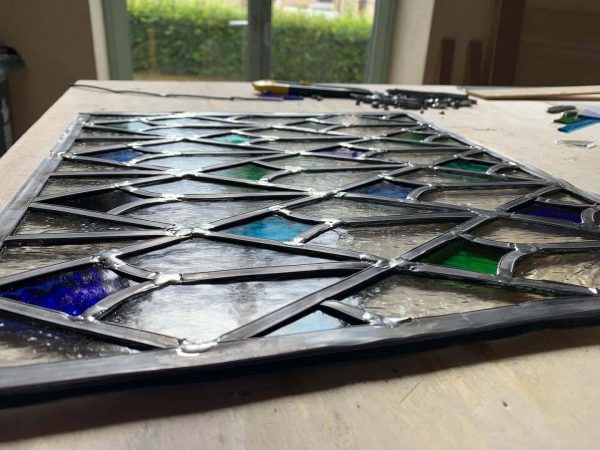 Vitrail assemblé au plomb dans un atelier de vitrailliste