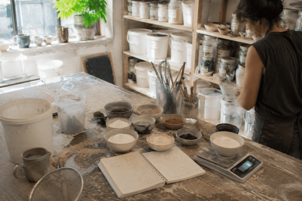 Artisane préparant des recettes d'émaux dans un atelier de céramique lors d'une formation professionnelle.