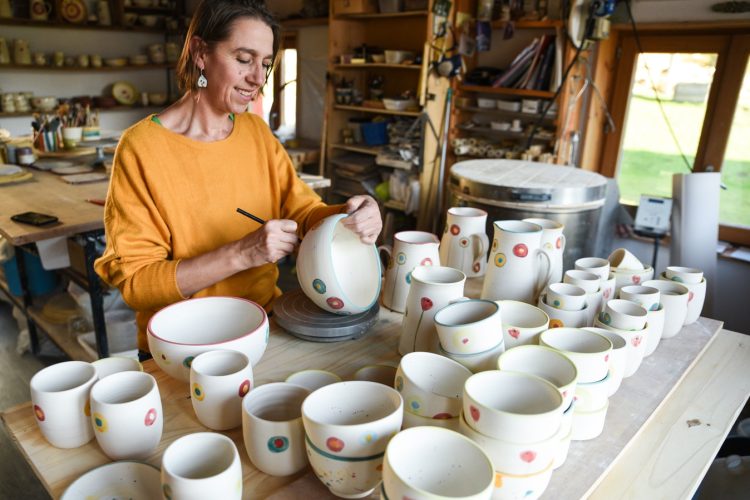 Céramiste décorant à la main une pièce en céramique dans son atelier.