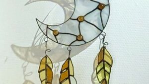 Vitrail en forme de lune blanche avec des plumes pendant l'atelier de vitrailliste à Tarbes